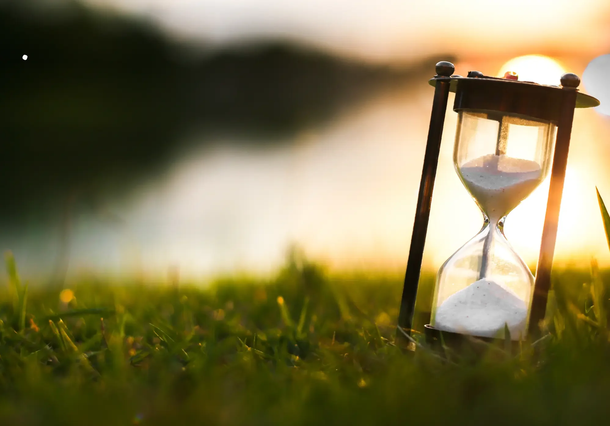 Hourglass at sunset representing urgency and time running out.