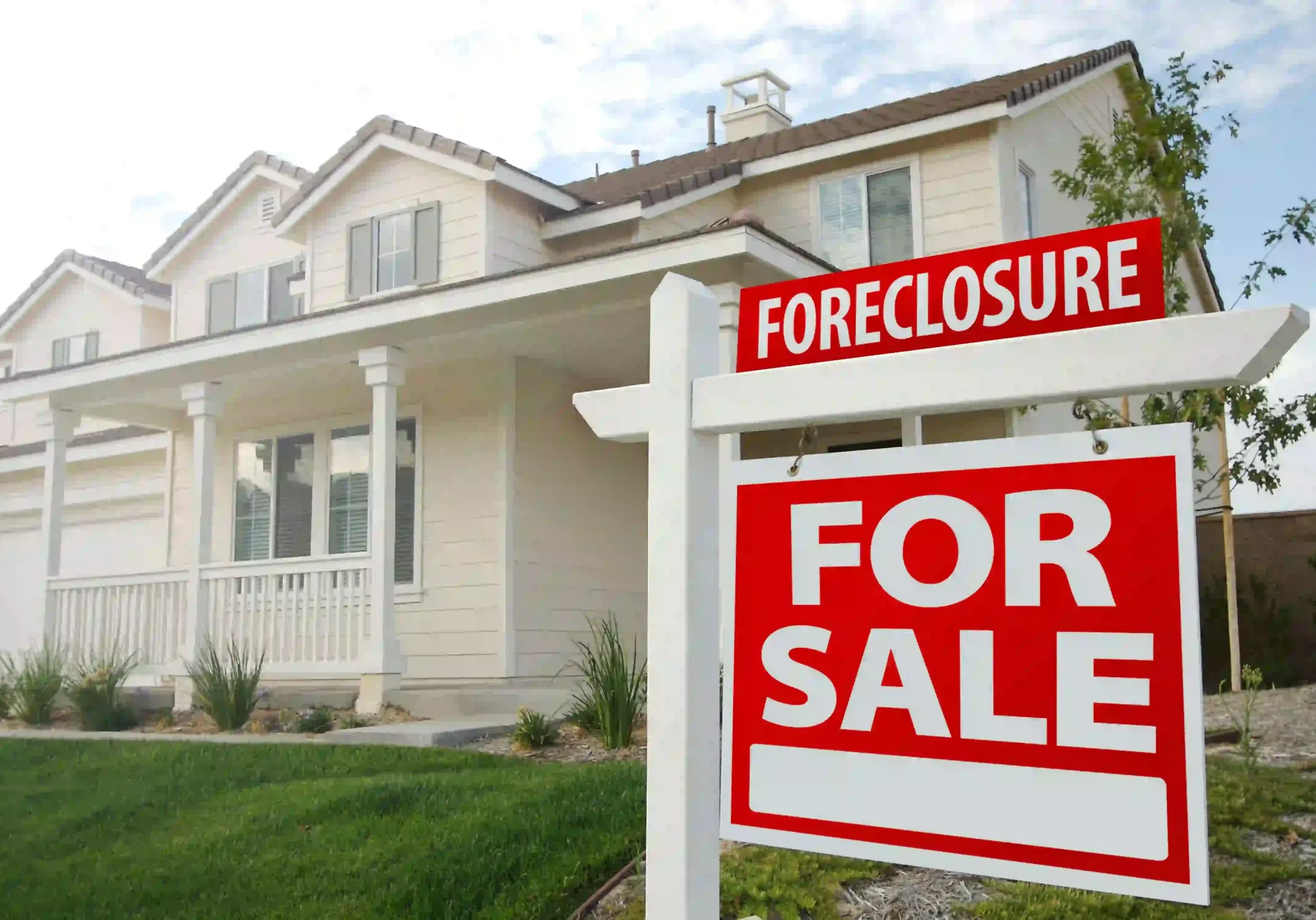 House for sale due to foreclosure with foreclosure sign on the lawn.